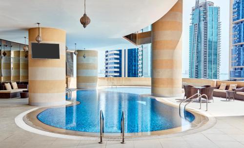 a swimming pool in a hotel lobby with tall buildings at Best Plaza West Bay Hotel in Doha