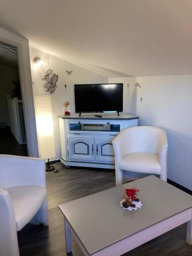 Una sala de estar con un televisor y dos sillas y una mesa. en Gite de la Streng, en Ribeauvillé