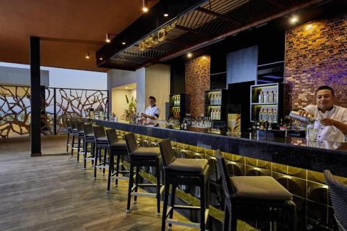 a bar with chairs and a man standing at a counter at Riu Palace Baja California - Adults Only - All Inclusive in Cabo San Lucas