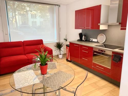 uma sala de estar com um sofá vermelho e uma mesa de vidro em Appart' Weekly Quartier Impérial Gare em Metz