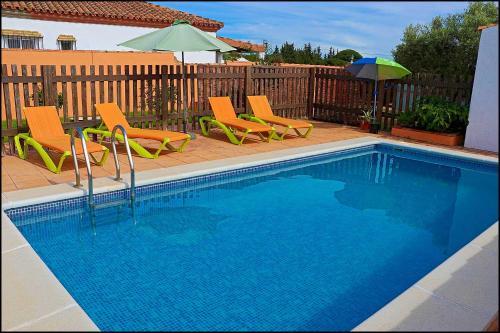 a swimming pool with two chairs and an umbrella and an umbrella at Chalet rústico Roche in Conil de la Frontera