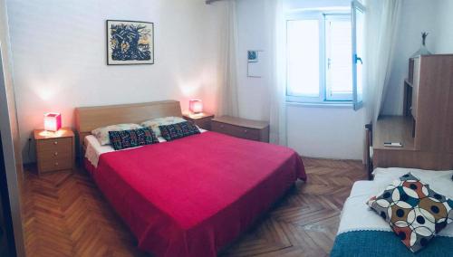 a bedroom with a large red bed and a window at Large Terrace Apartment in Korčula