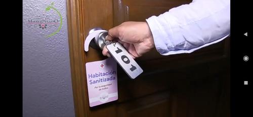 a person unlocking a door with a sign on it at Hotel del Marquesado in Oaxaca City