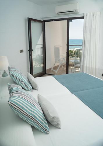 a white bed with pillows and a view of the ocean at Hostería del Mar in Peniscola
