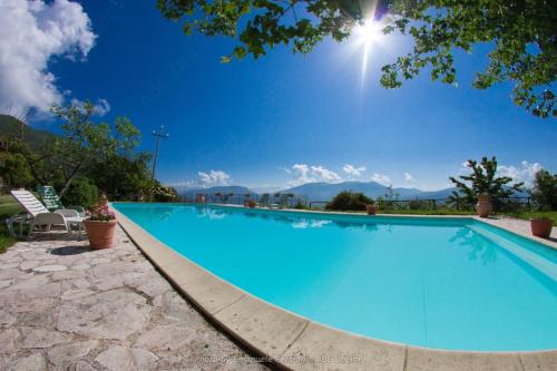 a large blue swimming pool with mountains in the background at Agriturismo Santa Serena in Cerreto di Spoleto