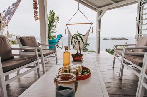 a living room with a table and chairs and the ocean at Sunset Palm - Villa Créole avec piscine face au coucher de soleil et à la réserve Cousteau in Bouillante