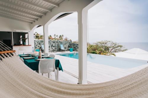 a hammock in a house with a swimming pool at Sunset Palm - Villa Créole avec piscine face au coucher de soleil et à la réserve Cousteau in Bouillante