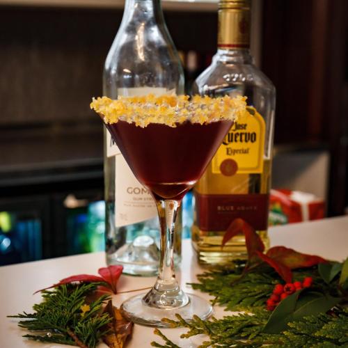 a drink in a martini glass next to a bottle of alcohol at Barnett Hill Hotel in Guildford