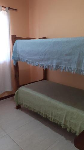 Una cama con una sábana azul encima.  en Bien al Sur en Villa Gesell