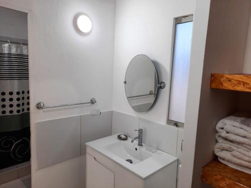 a white bathroom with a sink and a mirror at Hotel Villa Sirena in Vichayito