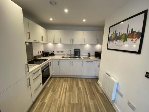 eine Küche mit weißen Schränken und Holzböden in der Unterkunft Park Central City Loft in Birmingham