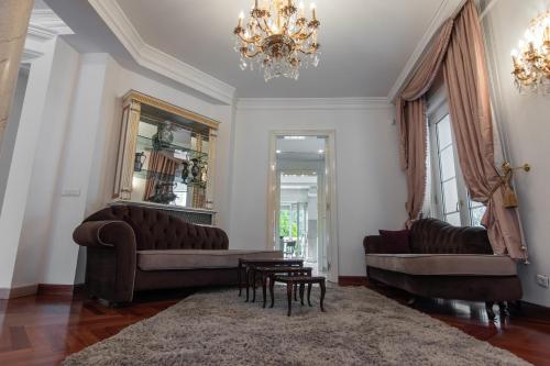 a living room with two couches and a chandelier at Villa Dedinje in Belgrade