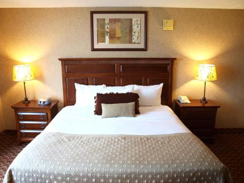 a bedroom with a large white bed with two lamps at Ramada by Wyndham Topeka Downtown Hotel & Convention Center in Topeka