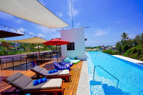 a swimming pool with lounge chairs and a red umbrella at Puerto Sayulita in Sayulita