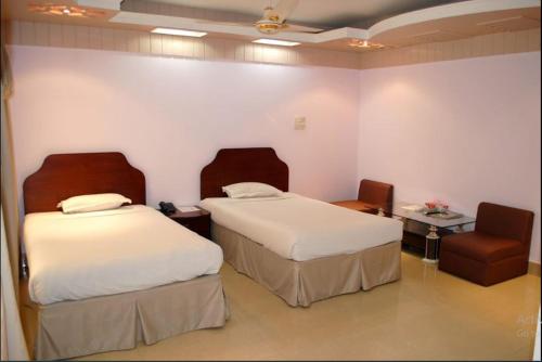 a hotel room with two beds and a chair at Naba Inn in Chittagong