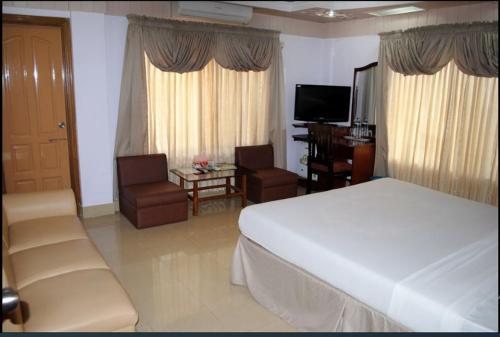 ein Schlafzimmer mit einem Bett und ein Wohnzimmer mit einem TV in der Unterkunft Naba Inn in Chittagong