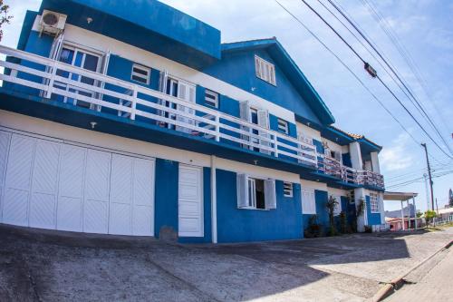 a blue and white house with white garage doors at Hotel Recanto do Mar in Capão da Canoa