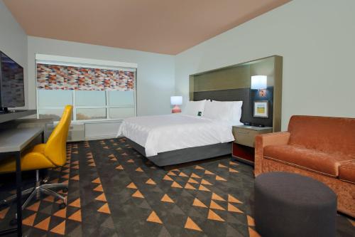 a hotel room with a bed and a desk and a couch at Holiday Inn Hattiesburg - North by IHG in Hattiesburg