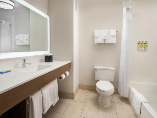 a white bathroom with a toilet and a sink at Holiday Inn Express Hotel & Suites Olive Branch by IHG in Olive Branch