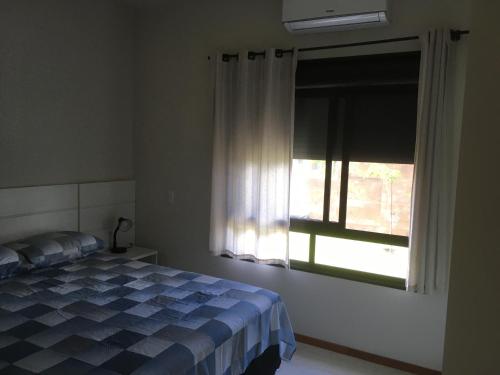 a bedroom with a bed and a window at Garopaba - Praia da Gamboa - Apartamento com piscina in Garopaba