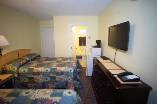 a hotel room with two beds and a flat screen tv at Stardust Motel in Camrose