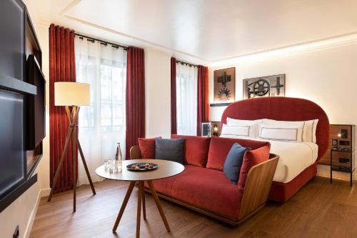 uma sala de estar com um sofá vermelho e uma cama em Villa Marquis Member of Meliá Collection em Paris