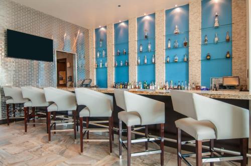 a bar with white chairs and a blue wall at Hotel Indigo Waco by IHG in Waco