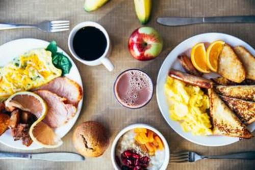 a table topped with plates of breakfast foods and coffee at Holiday Inn Lafayette North by IHG in Lafayette