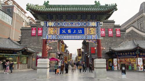 a gate in a city with people walking around at Holiday Inn & Suites Tianjin Downtown by IHG in Tianjin