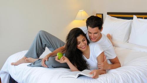 a man and woman laying on a bed reading a book at Phi Phi Holiday Resort-SHA Extra Plus in Phi Phi Islands