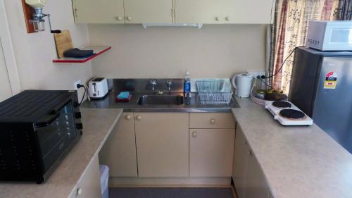 a small kitchen with a sink and a refrigerator at Riverside Accommodation in Karangahake
