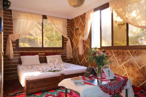 a bedroom with two beds and two tables and windows at Dar Adouss in Imlil