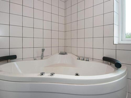 eine weiße Badewanne in einem weiß gefliesten Bad in der Unterkunft 8 person holiday home in Odder in Odder