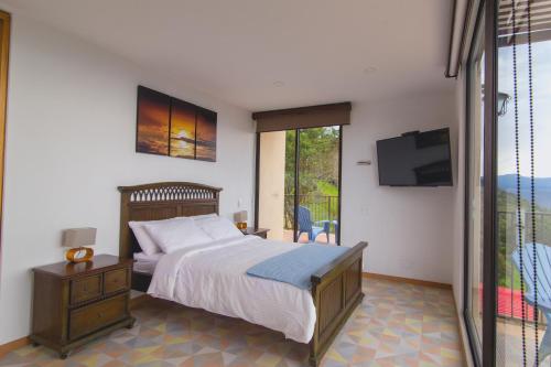 1 dormitorio con 1 cama, TV y balcón en Hotel Casa Portones en San Bernardo
