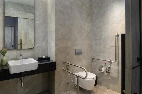 a bathroom with a sink and a toilet and a mirror at Holiday Inn & Suites Siracha Laemchabang by IHG in Si Racha