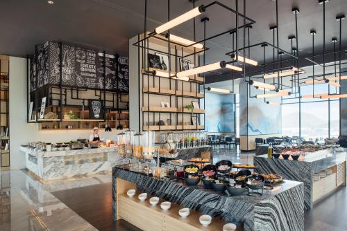 a restaurant with a counter with food on it at Holiday Inn & Suites Siracha Laemchabang by IHG in Si Racha