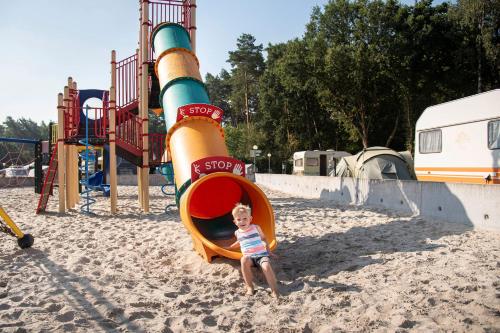 a young child sitting in a slide at a playground at Vakantiewoning Zavelbos in Maaseik