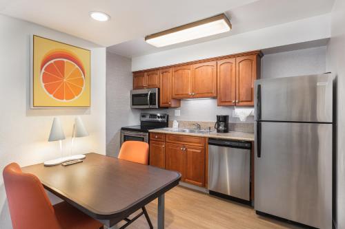 a kitchen with a table and a stainless steel refrigerator at Clementine Hotel & Suites Anaheim in Anaheim
