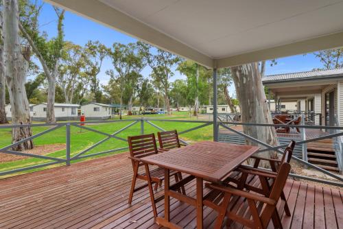 a wooden table and chairs on a deck with a park at Discovery Parks - Clare in Clare