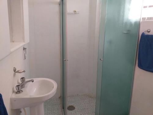 La salle de bains est pourvue d'un lavabo et d'une douche en verre. dans l'établissement Apartamento Carrinho do Kuko n 309, à Praia Grande