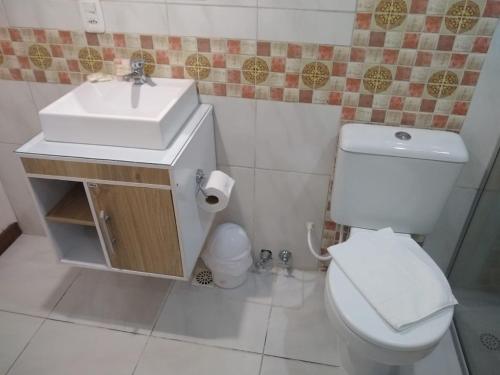 a bathroom with a white toilet and a sink at Casa do Lago in Gramado