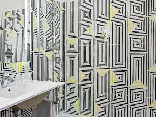 baño con lavabo y pared con estampado amarillo y negro. en ibis Styles Massy Opéra en Massy