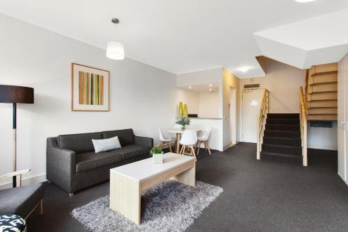 a living room with a couch and a table at Mercure Melbourne Albert Park in Melbourne