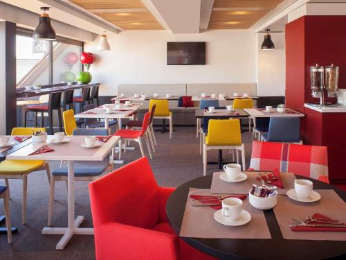 a restaurant with tables and colorful chairs and tablesktop at Mercure Strasbourg Centre in Strasbourg
