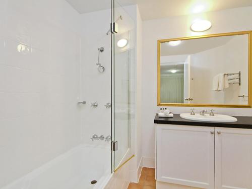 a bathroom with a sink and a shower with a mirror at Calypso Plaza Resort Unit 141 in Gold Coast