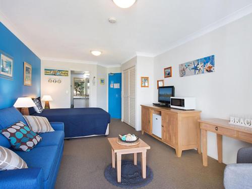 a living room with a blue couch and a tv at Calypso Plaza Resort Unit 215 Beachfront Studio Apartment in Gold Coast