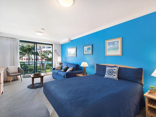 Calypso Plaza Resort Unit 215 في غولد كوست: غرفة نوم زرقاء مع سرير وأريكة