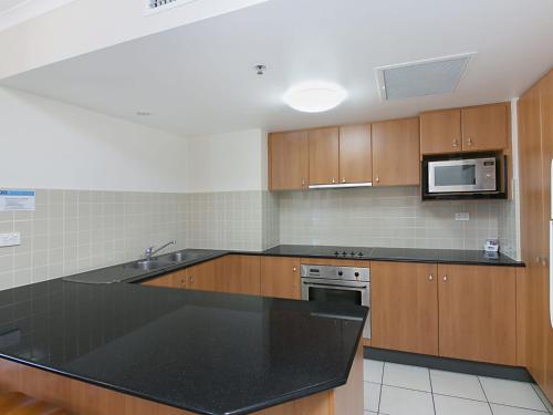 a kitchen with a black counter top and a microwave at Calypso Tower Unit 807 in Gold Coast