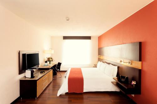 a hotel room with a bed and a television at Mercure Bogota BH Retiro in Bogotá