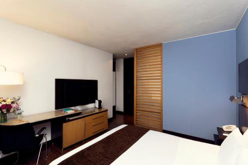 a hotel room with a bed and a desk and a television at Mercure Bogota BH Retiro in Bogotá
